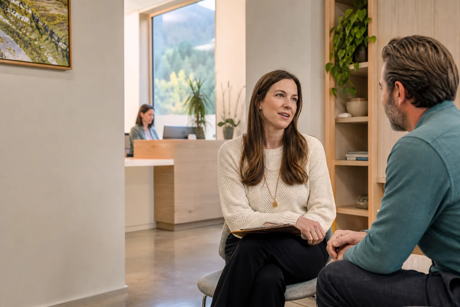 A wellness clinician in conversation with a client while clinic operations continue in the background